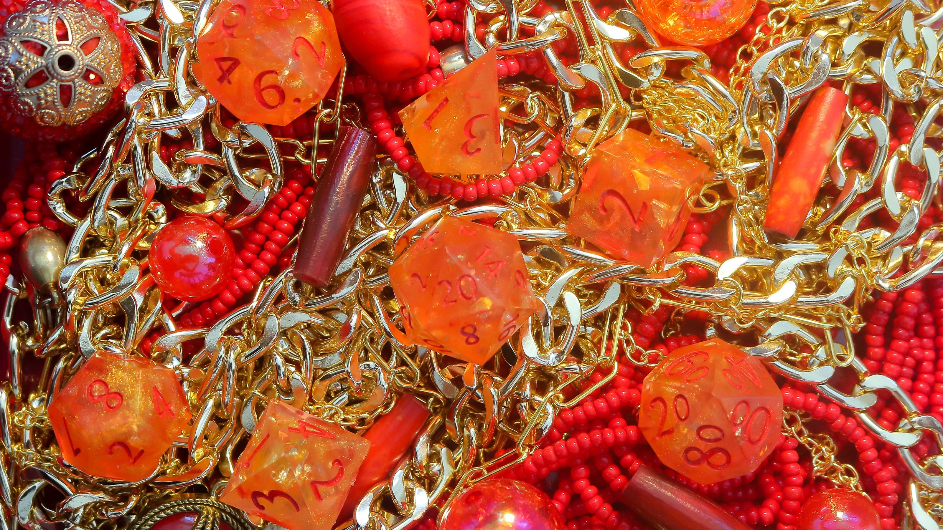 Chains, beads, and dice in reds and golds resembling a dragon's hoard.
