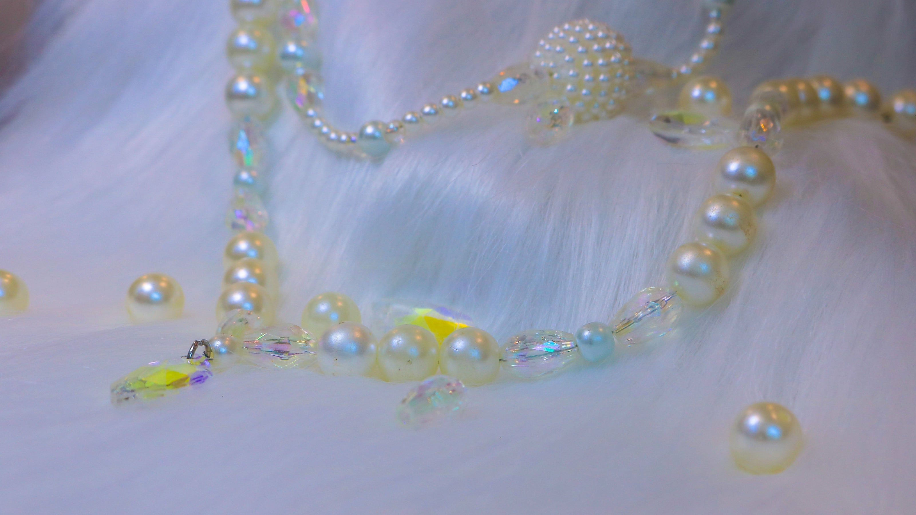 A pearl and iridescent necklace laid on a fur background.